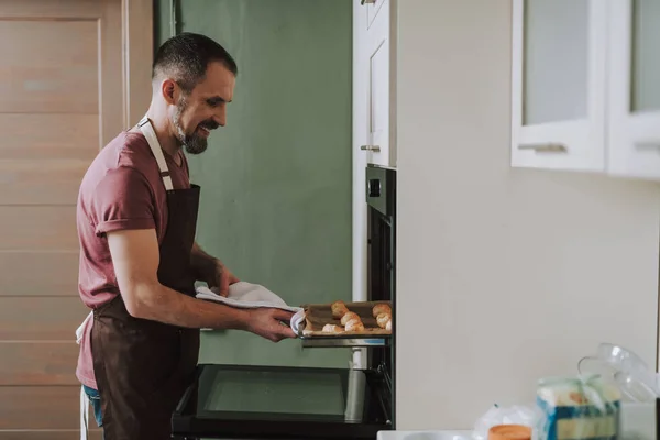 Cintura hacia arriba del hombre alegre tomando bandeja para hornear del horno — Foto de Stock