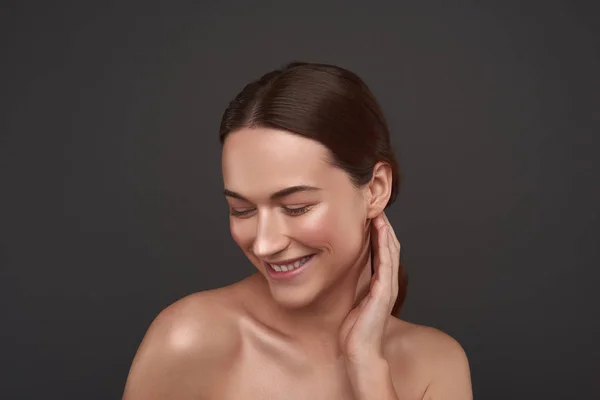 Vrolijke mooie meid met natuurlijke make-up poseren tegen grijze achtergrond — Stockfoto