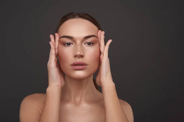 Atractiva joven con maquillaje natural que mantiene las manos en sus sienes — Foto de Stock