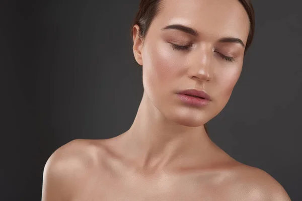 Charmante jeune femme aux yeux fermés debout sur fond gris — Photo