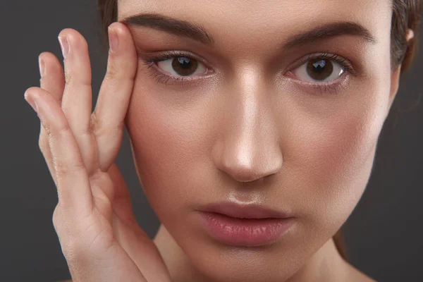 Gyönyörű fiatal nő húz bőr közelébe szeme — Stock Fotó