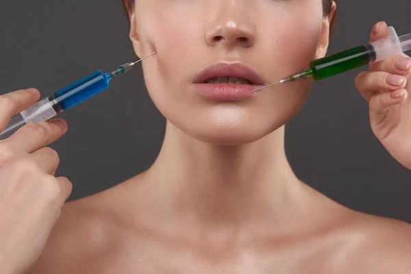 Schoonheidsspecialiste handen geven injectie in kin en lippen van jonge vrouw — Stockfoto