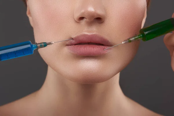 Beautician making injections in lips of young woman