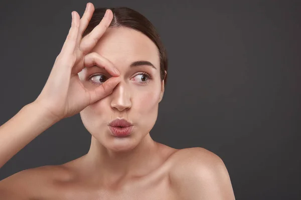 Vacker ung kvinna omslutande hennes öga med fingrarna — Stockfoto