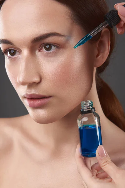 Esteticista aplicando suero vitamínico en la cara de la bella dama —  Fotos de Stock