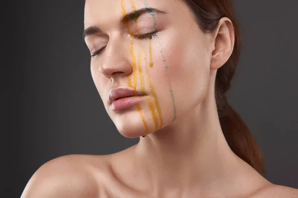 Mooie serene dame met oranje en blauwe vloeistof druipend van haar gezicht — Stockfoto