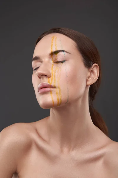 Serena dama desnuda con líquido naranja y azul goteando de su cara — Foto de Stock