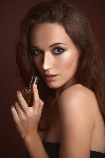 Όμορφη νεαρή γυναίκα με καπνό μάτια μακιγιάζ κρατώντας άρωμα — Φωτογραφία Αρχείου