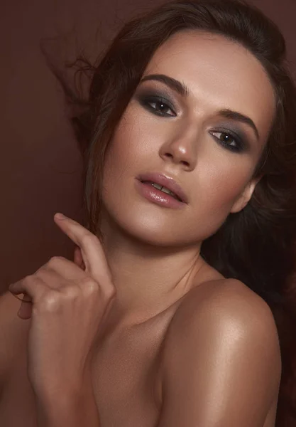 Vacker ung kvinna med Smokey Eyes makeup poserar mot brun bakgrund — Stockfoto