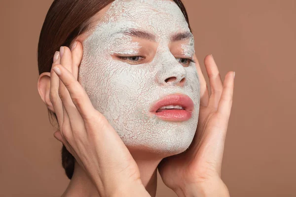 Zamyšlená žena dotýkala se její kůže s obličejní maskou — Stock fotografie