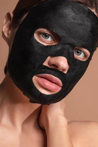 Portrait of the woman having black sheet mask on her face — Stok Foto
