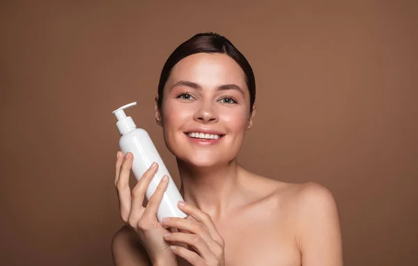 Mujer con hombros desnudos sosteniendo botella blanca con dispensador —  Fotos de Stock