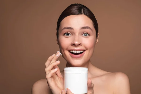 Opgewonden vrouw met behulp van gezichtscrème uit de witte pot — Stockfoto