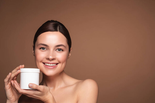 Emotional woman standing with face cream and smiling