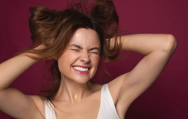 Expressieve vrouw glimlachend en knoeien haar haar omhoog — Stockfoto