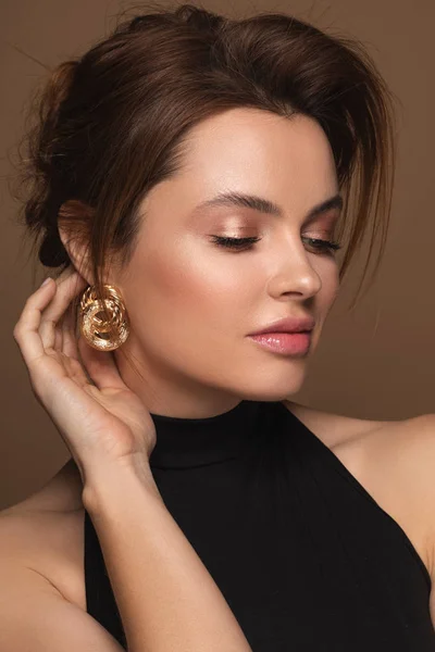 Vacker kvinna i svart klänning och med gyllene örhängen — Stockfoto