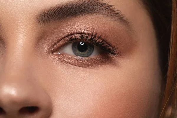 Auge der Frau mit glänzenden Lidschatten und schwarzer Wimperntusche — Stockfoto