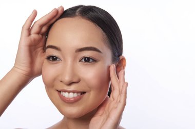 Neşeli genç bayan yüzüne dokunuyor ve mutlu görünümlü