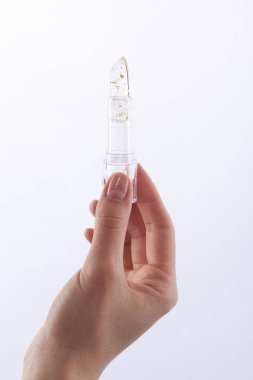 Parıltılı şeffaf ruj tutan kadının eli