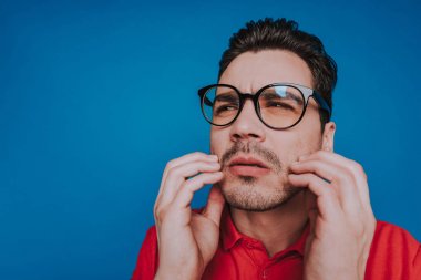 Mavi arka planda gözlüklü Kafkas adam düşük açı
