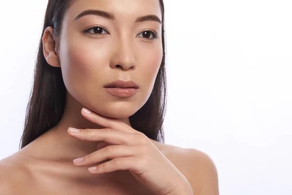 Serious Asian woman looking into the distance and touching her chin — Stock Photo, Image