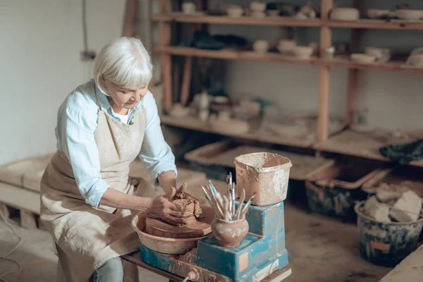 Обрезанное фото пожилой ремесленницы, делающей декоративную чашу в мастерской гончаров — стоковое фото