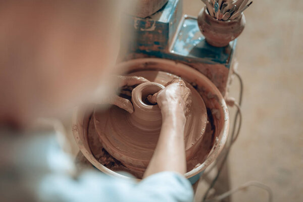 Обрезанное фото женских рук, формирующих кувшин в мастерской
