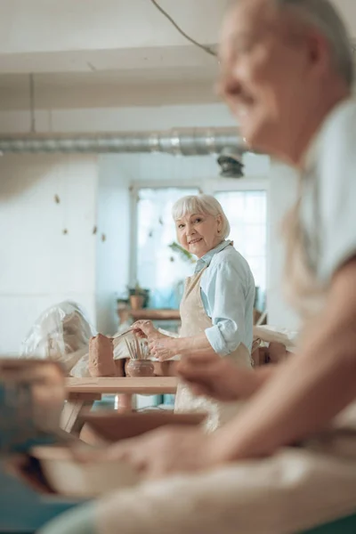 Hüfte hoch von lächelnder älterer Handwerkerin beim Bemalen von Steingut im Töpferatelier — Stockfoto