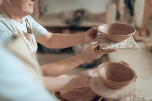 Alto ángulo de artesano masculino mirando su cuenco de cerámica en el taller — Foto de Stock