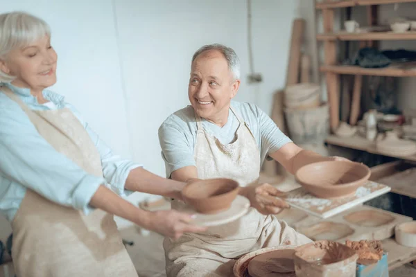 Alto ángulo de dos maestros de arcilla mostrando sus obras en el estudio de alfareros — Foto de Stock