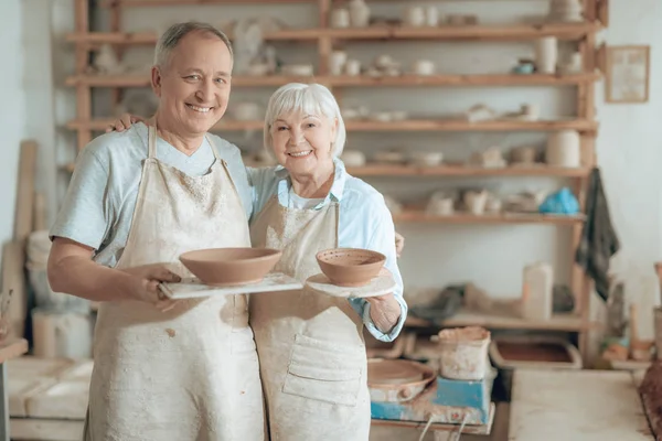 Ancianos maestros de arcilla feliz mirando a la cámara y mostrando su trabajo — Foto de Stock