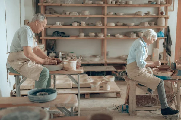 Vista laterale di due vasai che fabbricano terracotta e lavorano nel loro laboratorio — Foto Stock
