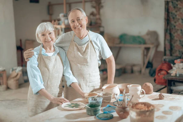 Halbe Länge glücklicher reifer Töpfer, die in der Werkstatt in die Kamera schauen — Stockfoto