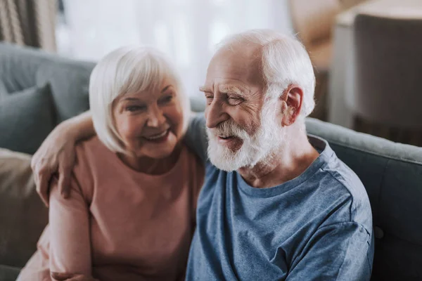 Alegre pareja de ancianos abrazándose en el sofá en casa —  Fotos de Stock