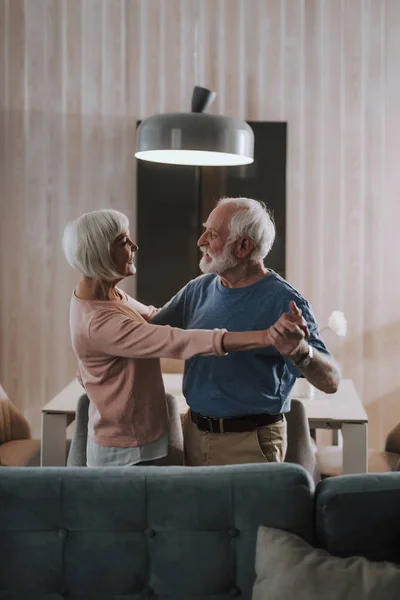 Happy elder couple dancing in living room