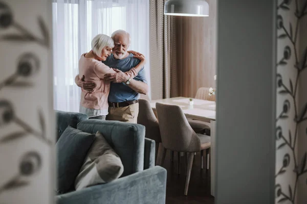 Positivt äldre par som omfamnar i vardags rummet — Stockfoto