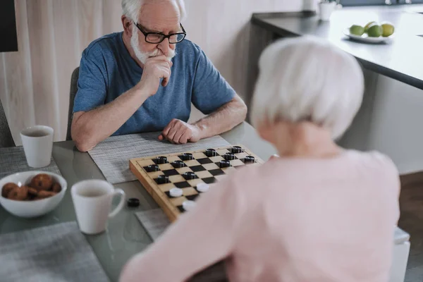 Emeklici çift ev mutfakta çek oynuyor — Stok fotoğraf