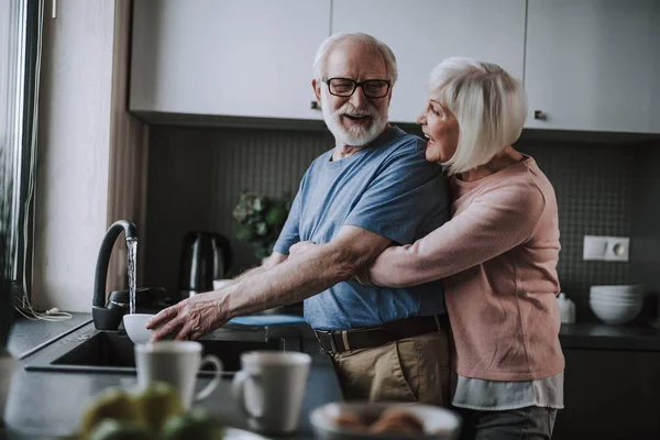 Senior paar genieten van afwas gerechten op keuken — Stockfoto