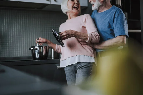 Счастливая смеющаяся старшая пара готовит на кухне — стоковое фото