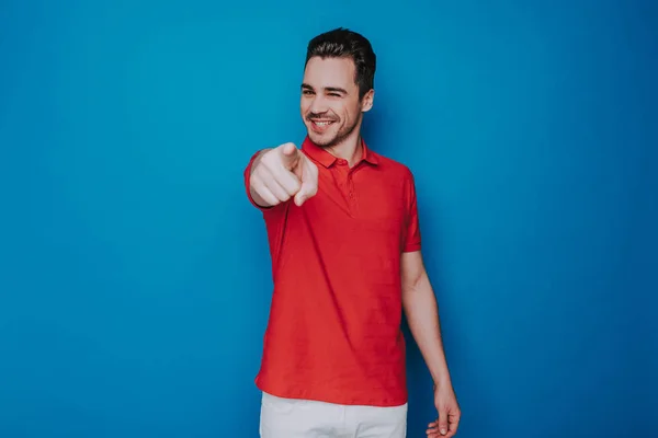 Half length of young smiling guy pointing finger at viewer in studio — Stock Photo, Image