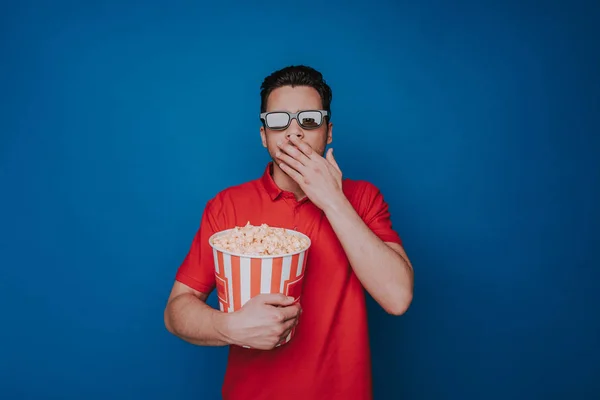 Талія здивований Кавказький людина Холдинг попкорн відро на синій фон — стокове фото