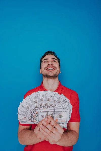 Retrato de la cintura hacia arriba del tipo feliz sin afeitar manteniendo el dinero en brazos en el interior —  Fotos de Stock