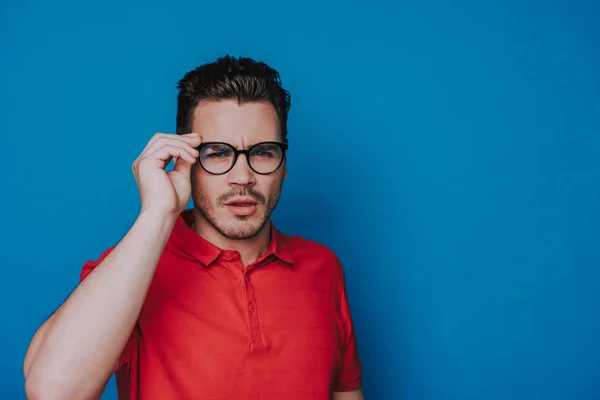 Demi longueur de beau gars dans lunettes plissant sur fond bleu — Photo