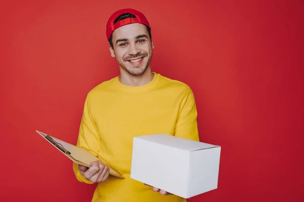긍정적 인 젊은 사람 에 캡 보유 a 상자 과 클립 보드 에 팔 — 스톡 사진