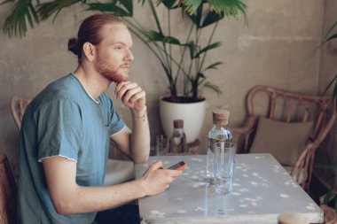 Telefon ile genç adam kafede zaman geçiriyor