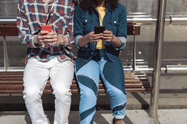 İki genç otobüs durağına akıllı telefonlar kullanıyor