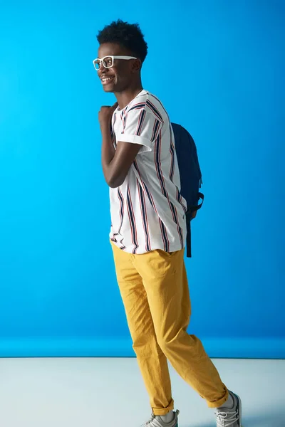 Glimlachende Afro man poseren met rugzak op blauwe achtergrond — Stockfoto