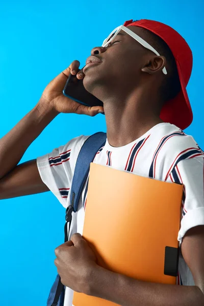 Афроамериканский студент с рюкзаком разговаривает на смартфоне — стоковое фото