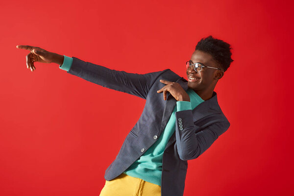 Waist up portrait of happy man moving to the rhythm of music. He is wearing in jacket and smiling. Copy space in left side
