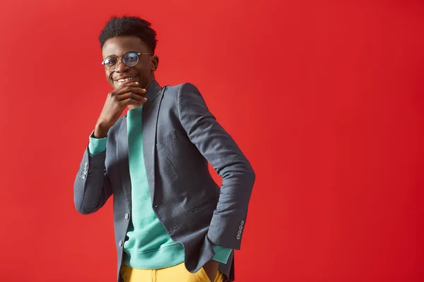 Joven positivo en gafas bailando sobre fondo rojo — Foto de Stock